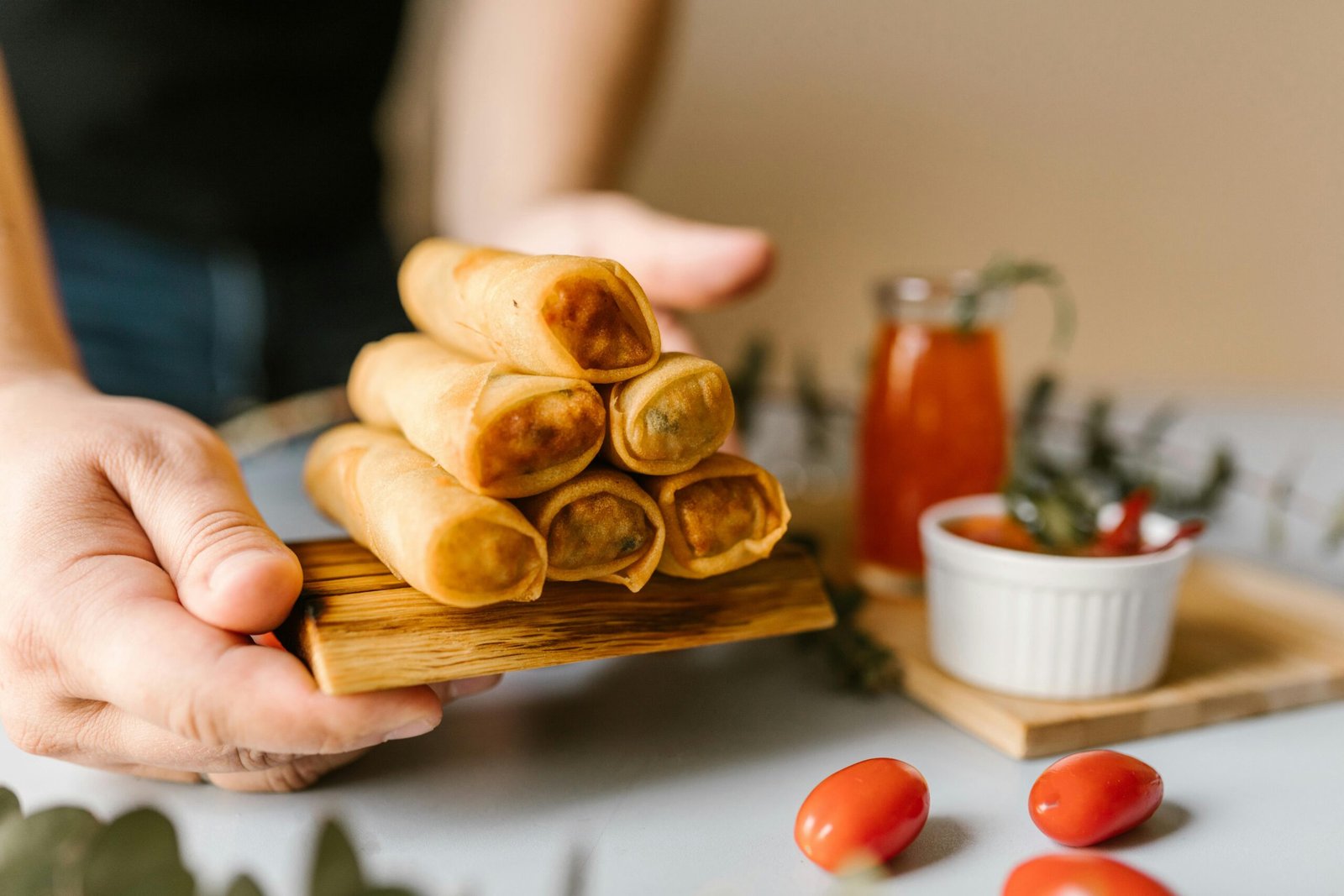 Close-up of crispy spring rolls served with dipping sauce and garnishes.